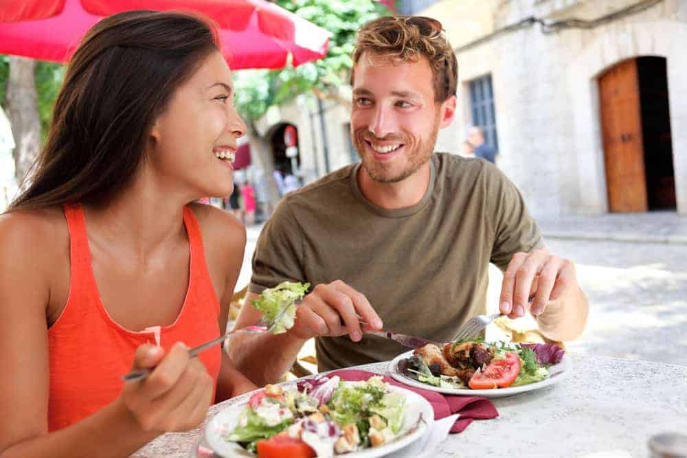 Man and woman eating lunch at outdoor cafe.